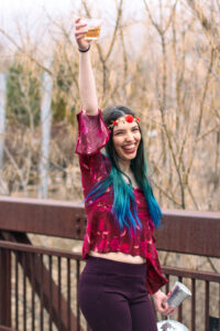 Woman dressed in disco and groovy clothes cheers while smiling at Zoo Brew cheers at Utah's Hogle Zoo